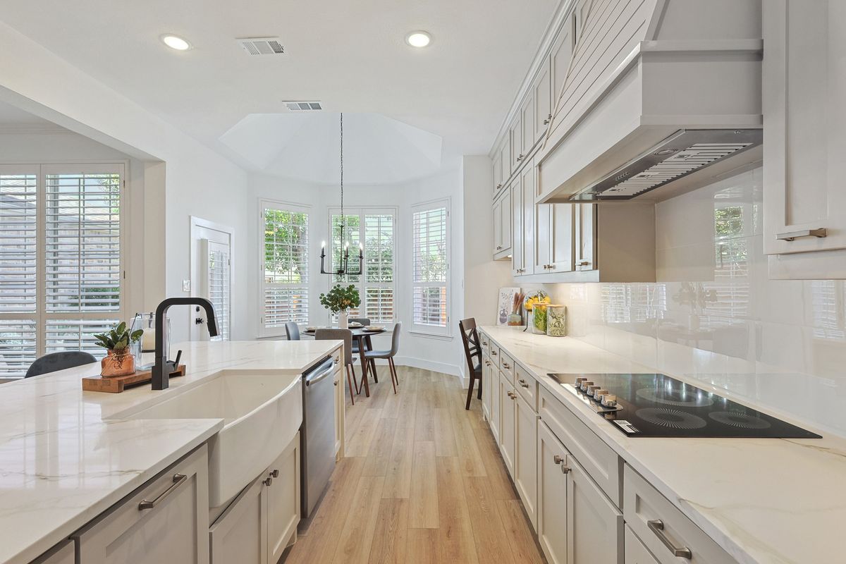 White kitchen with quartz counters and vent hood
