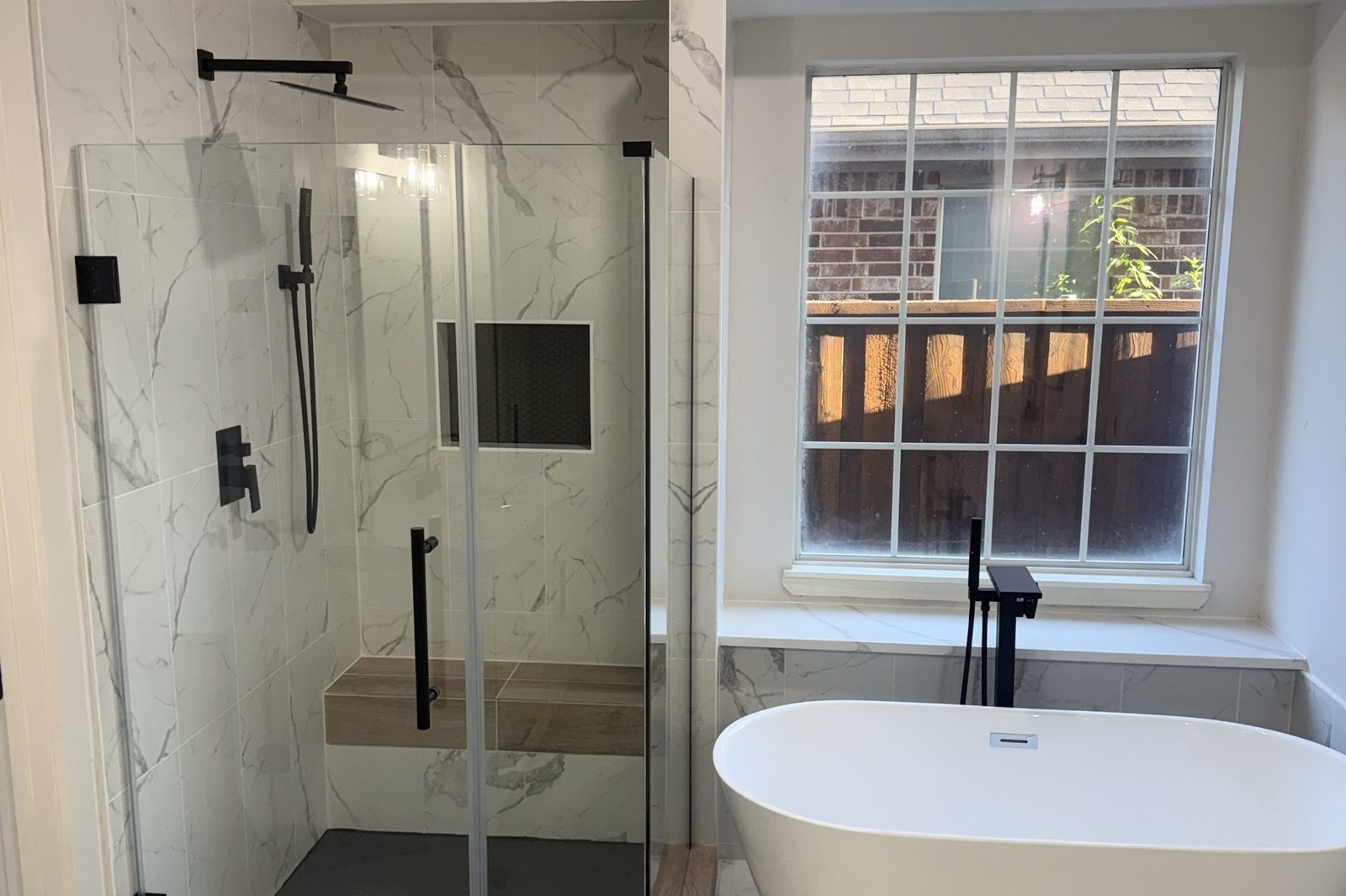 Renovated primary bath with marble walls and freestanding tub