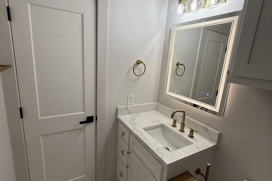 Bathroom with brass fixtures and marble tub surround