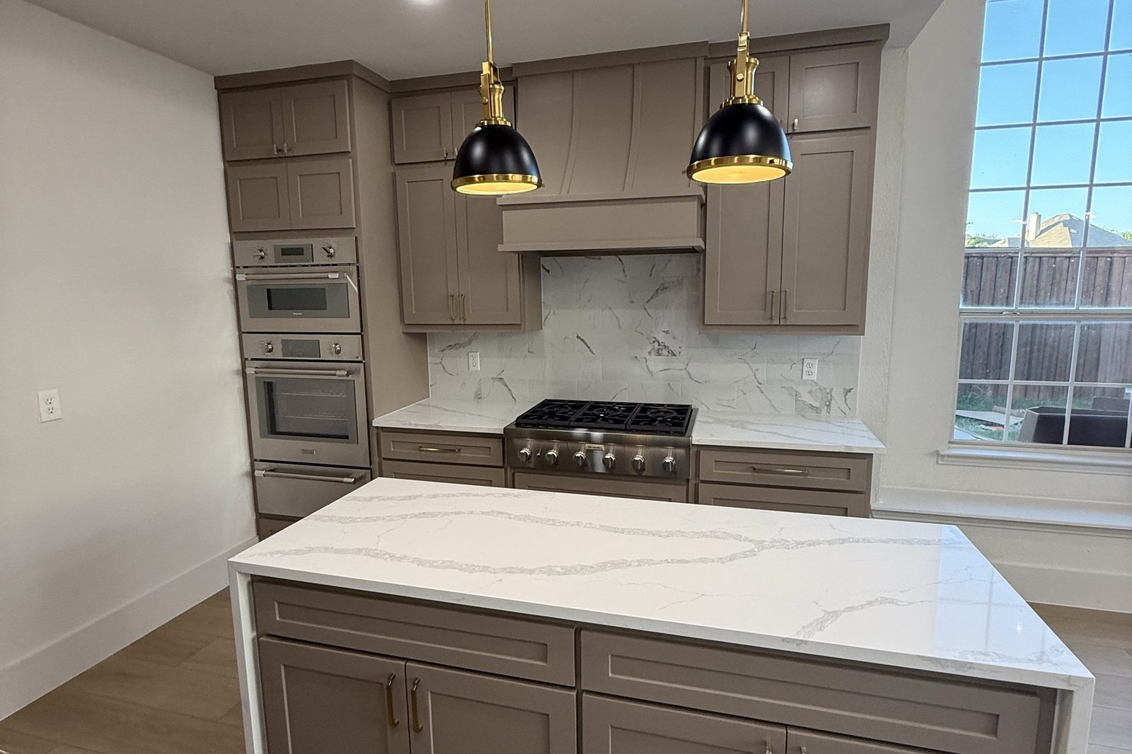 Custom kitchen with waterfall island and brass pendants